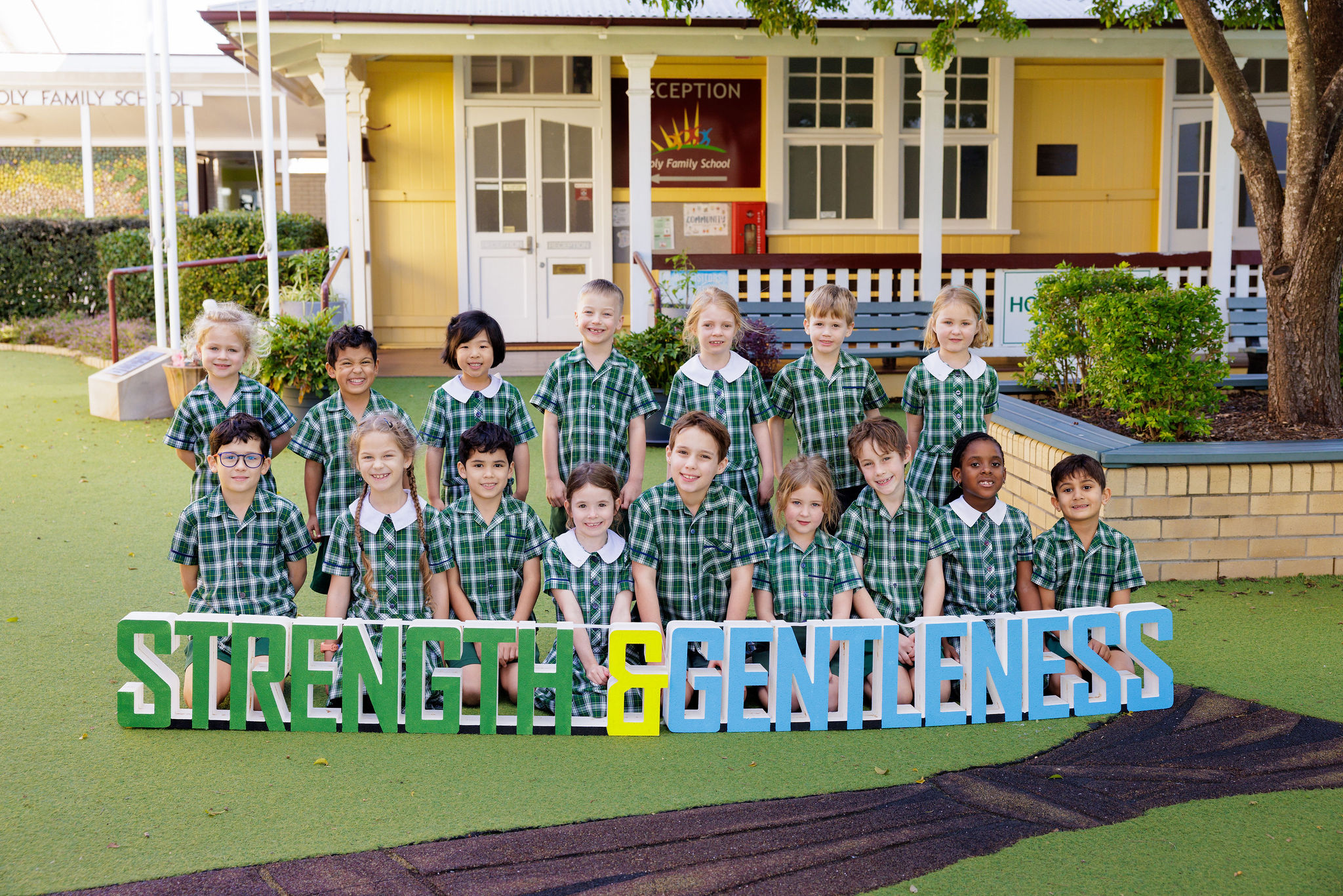 students sitting and standing behind a sign