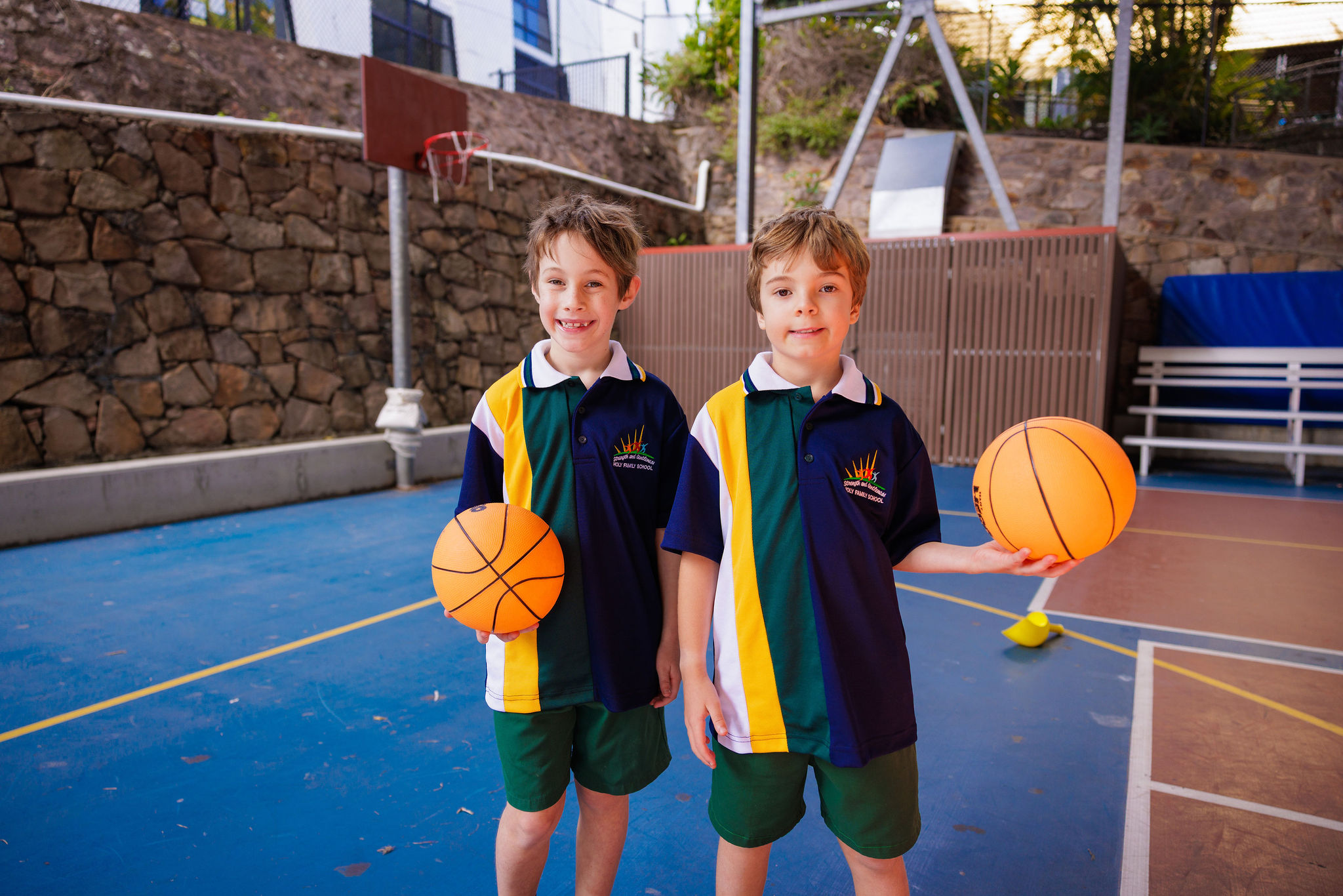 Students standing together on a school netball court holding basketballs, highlighting participation in sport, teamwork and active learning within the primary school environment