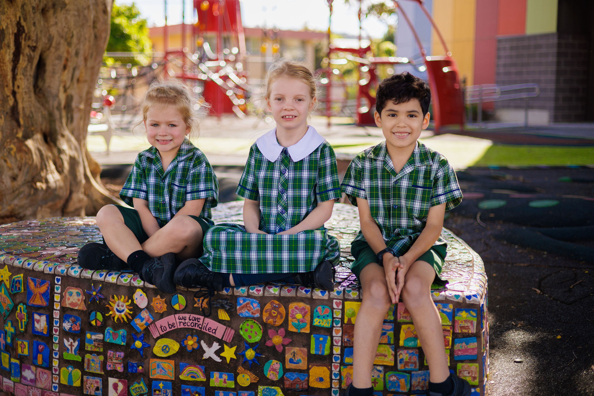 Students sitting together on a mosaic bench in the playground, highlighting friendship, belonging and positive relationships within the Holy Family Primary School Indooroopilly community