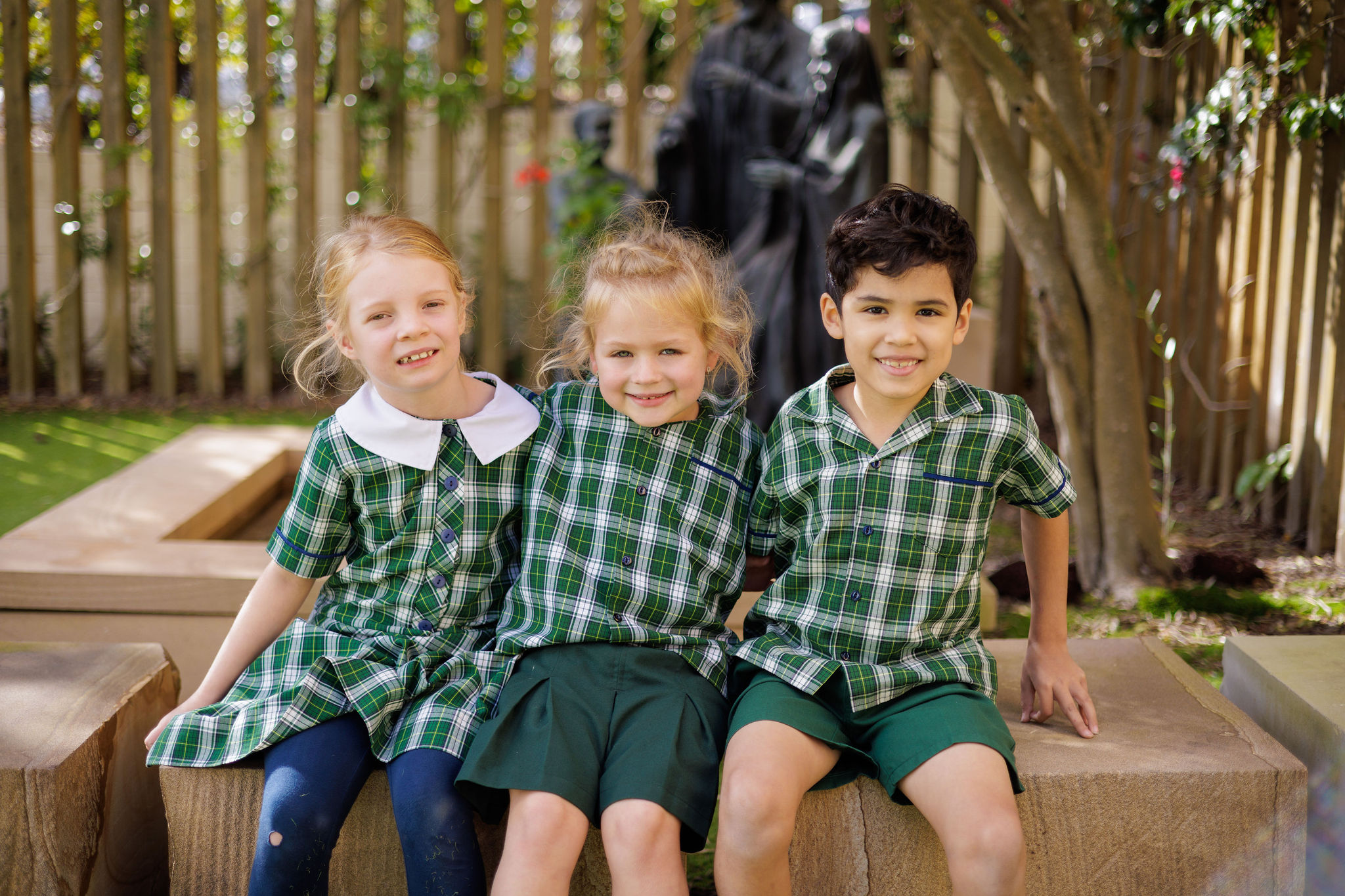 Students sitting together outdoors near a statue, highlighting friendship, belonging and a calm, welcoming learning environment within the primary school community
