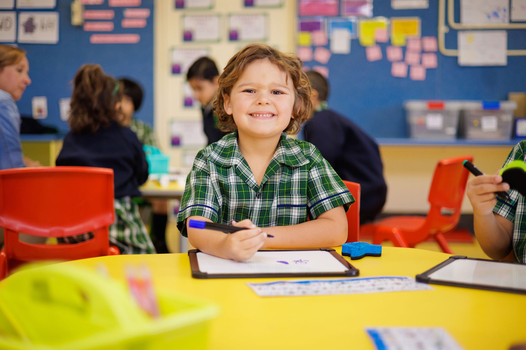 a boy smiling writing on a white board